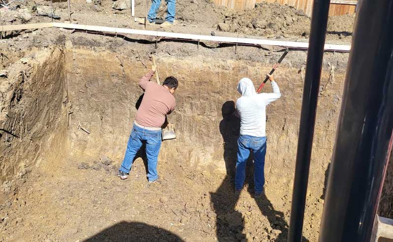 Construction crew hand-digging a gunite pool excavation in a Sacramento backyard