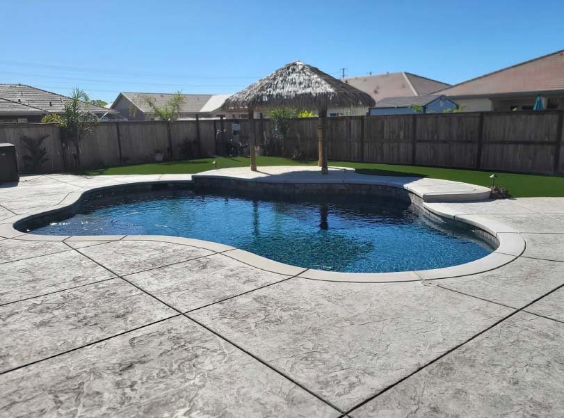 Rectangular pool with attached spa and stone waterfall feature in a rural Sacramento-area backyard