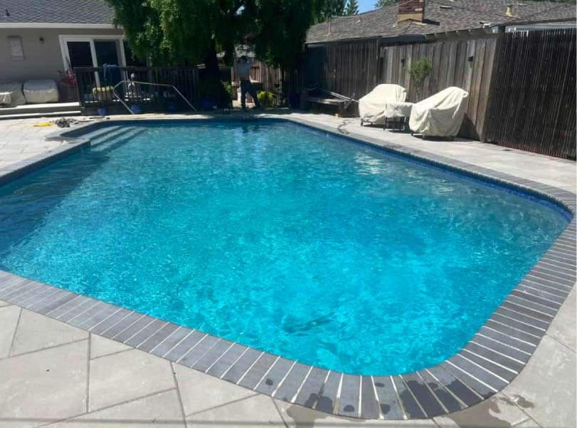 pool and raised square spa with twin stacked-stone water features on a paver patio