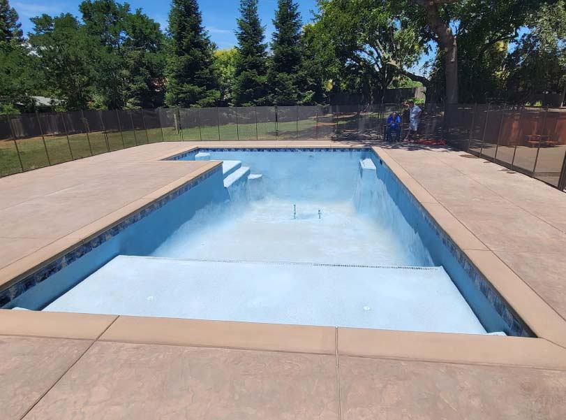 Freeform pool shell and concrete deck poured during construction in a two-story Sacramento home's backyard